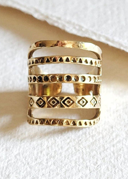 Gold ring with geometric patterns on a white fabric background