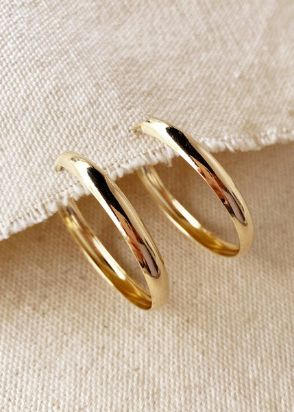 Gold hoop earrings on a beige fabric background