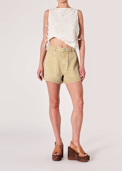 Person wearing a white sleeveless top and beige shorts on a plain background