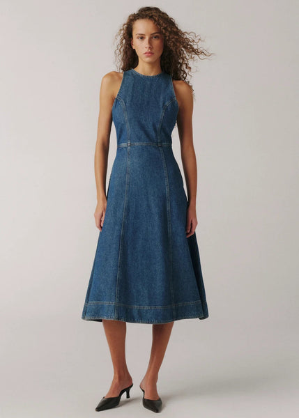 Woman wearing a blue denim dress on a plain background