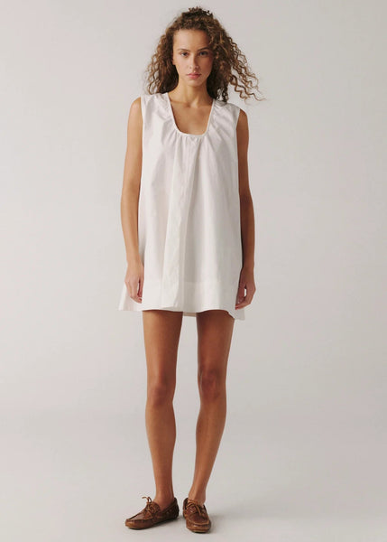 Woman wearing a white sleeveless dress on a plain background