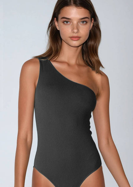 Woman wearing a black one-shoulder swimsuit against a light gray background
