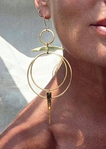 Close-up of a person wearing gold hoop earrings with a blurred background