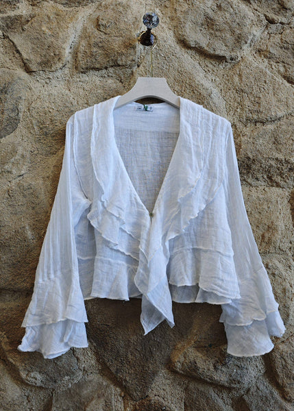 White ruffled top on a hanger against a stone wall