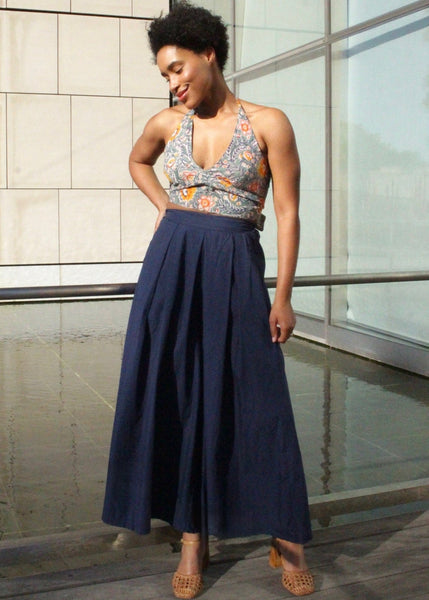 Woman wearing a floral top and navy skirt standing indoors.