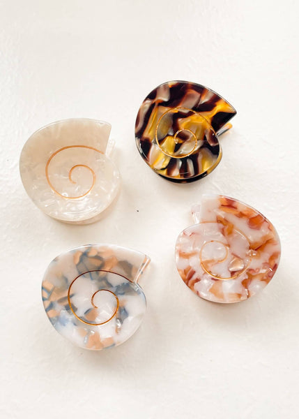 Four shell-shaped objects with tortoiseshell and natural patterns on a white background