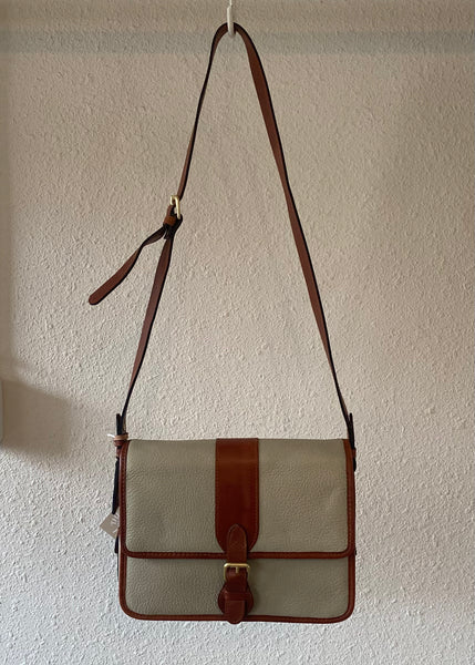 Canvas bag with brown leather accents hanging against a plain wall.