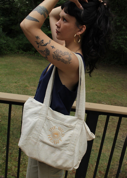 Person holding a white tote bag with text outdoors