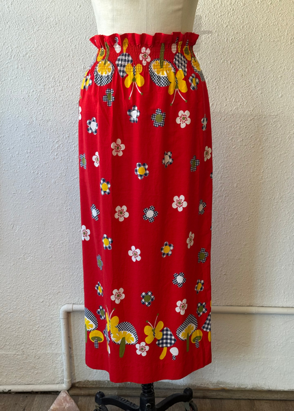 Red skirt with colorful pattern on a mannequin against a white wall.
