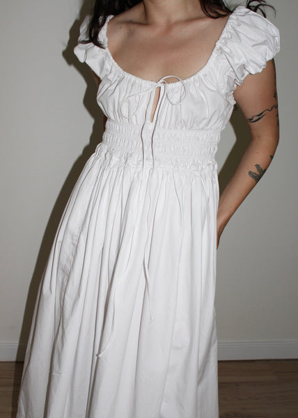 White dress with ruffled sleeves worn by a person against a plain background