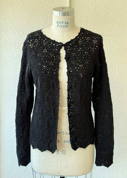 Black knit cardigan on a mannequin against a beige wall
