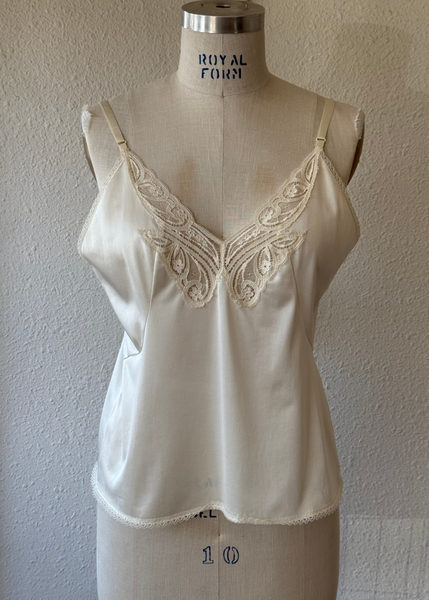 White lace-trimmed top on a mannequin against a plain wall.