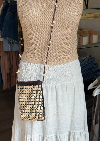 A beige sleeveless knit top displayed on a mannequin torso, paired with a white skirt and a small woven crossbody bag with a dark strap and beige beads. The mannequin is labeled ROYAL FORNY.