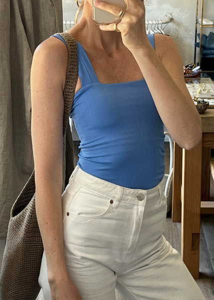 Person wearing a blue top and white pants taking a mirror selfie.