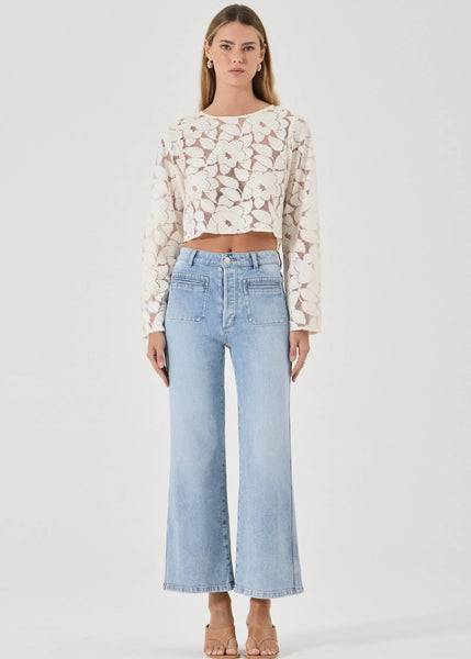 Woman wearing a floral blouse and light blue jeans on a white background