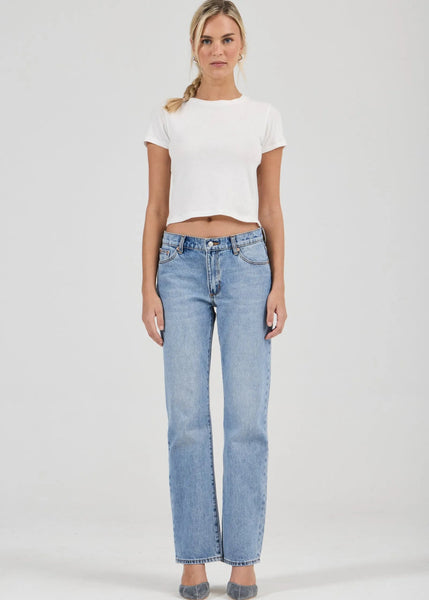 Woman wearing a white t-shirt and light blue jeans on a plain background