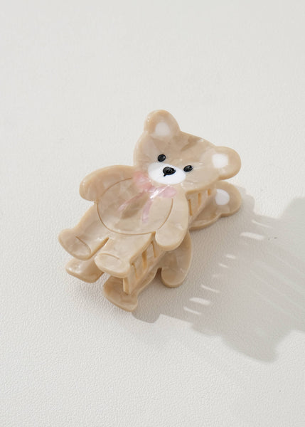 Beige teddy bear-shaped hair clip on a light gray background