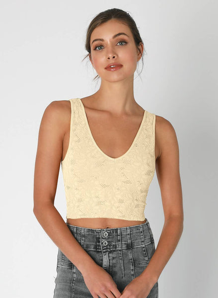 Woman wearing a beige lace top with gray jeans on a white background